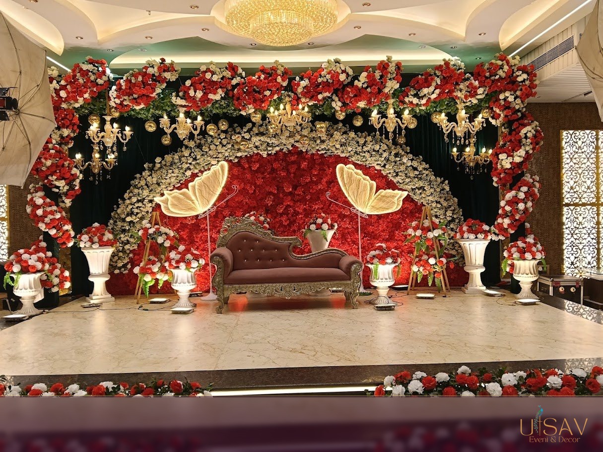 Luxury crimson floral reception stage with chandeliers and illuminated butterflies created by Utsav Event and Decor in Kolkata